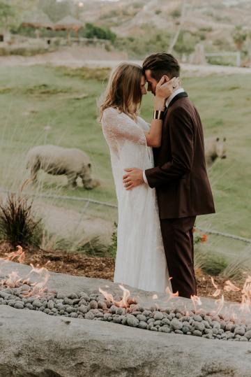 Bride and groom by fire pit with Rhinos at Kijamii Overlook
